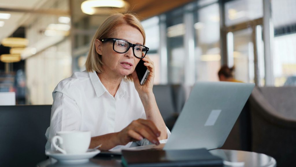 a woman sitting at a table talking on a cell phone