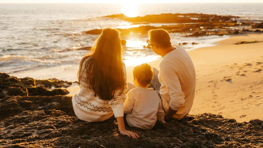 a family sitting on the beach at sunset