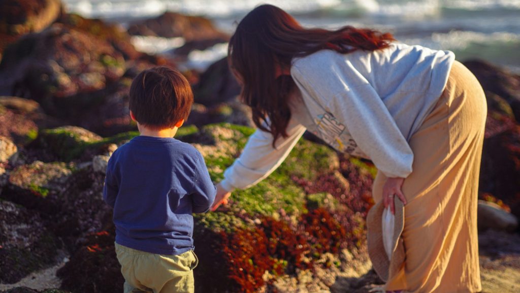 A woman and a child on a rocky beach